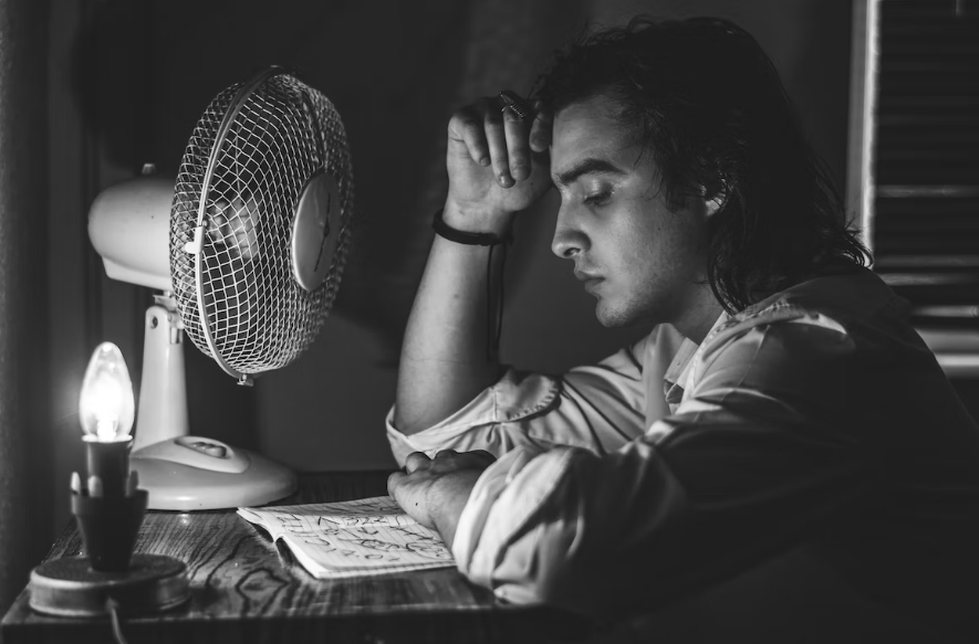 A man using a fan due to faulty air conditioning